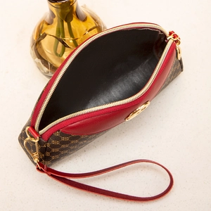Detailed macro view of the brown monogram clutch with red leather trim and golden zipper