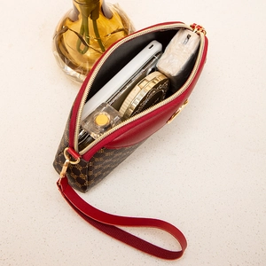 Detail view of stylish shell bag interior with phone and cosmetics on stone surface