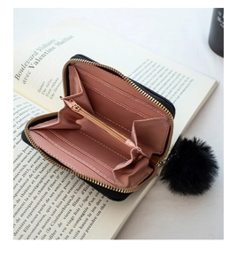 Detail of black woven wallet featuring pink lining, card slots, and a soft faux fur pompom