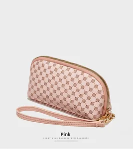 Détail d'une pochette en cuir PU rose avec motif géométrique et dragonne fine