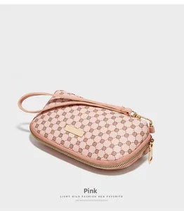 Détail du portefeuille rose en cuir PU avec motifs trèfles bruns et zip doré