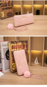 Details der rosa gesteppten langen Brieftasche mit V-Stich-Struktur und Pompon-Anhänger
