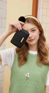 Detail of black quilted PU leather coin purse with golden bar and faux fur pompom