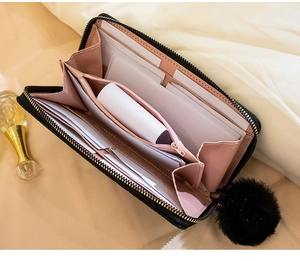 Detailed view of women's black long wallet with pink interior, card slots, and fur pompom