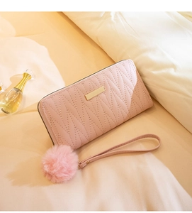 Detailed view of pink quilted long wallet with golden zipper and fluffy pom pom strap