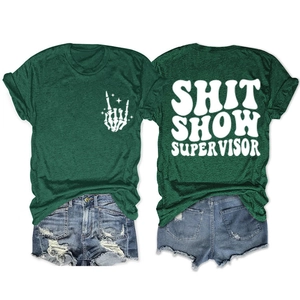 Flat lay of green t-shirt with SHIT SHOW SUPERVISOR print and ripped denim shorts