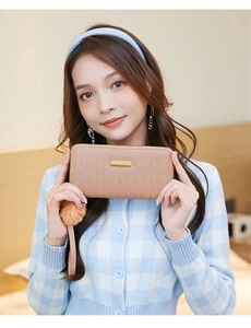 Detail of pink quilted long wallet with golden plate, wristlet and fluffy pompom charm