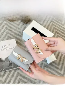 Détail de portefeuilles courts en cuir avec nœud doré en couleurs rose et gris
