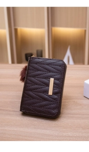 Close-up of diamond-quilted leather wallet with gold buckle and fluffy fur ball detail