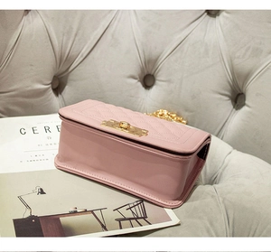 Detail van roze gewatteerde crossbodytas met gouden sluiting en ketting op bank