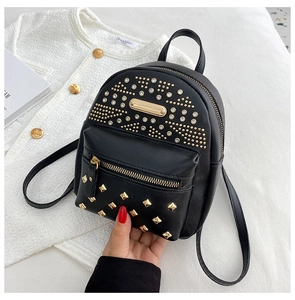 Detail of black PU leather mini backpack featuring gold rivet studs and zipper pocket