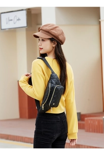 Détail du sac banane noir matelassé avec zips dorés porté par un mannequin en ville