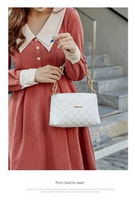 Close-up of white quilted handbag with chunky gold chain strap on orange dress