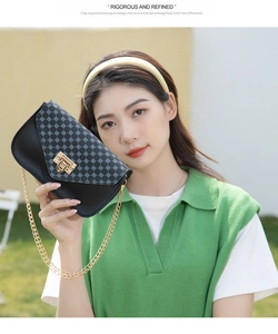 Close-up of a black crossbody bag with grey geometric pattern and golden lock clasp