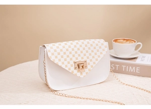 Detail of white faux leather crossbody bag with brown print and gold metal lock clasp