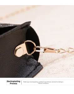 Detail of multi-layer plated gold metal D-ring and chain on black leather crossbody bag