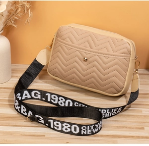 Close-up of khaki V-quilted faux leather bag with wide letter print fabric strap