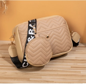 Detail of beige V-quilted camera bag with detachable round coin purse and logo strap