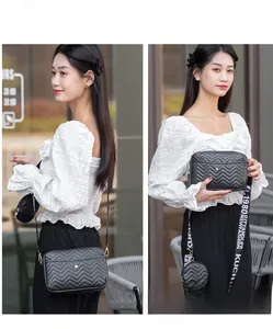 Detail of black V-quilted crossbody bag with a round coin pouch and wide graphic strap