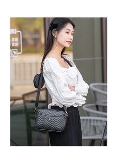 Detail of black V-quilted crossbody bag with matching round coin purse on wide strap