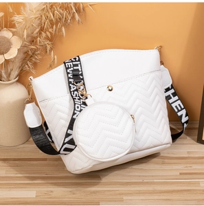 Détail du sac seau blanc matelassé avec coutures en V et sangle à lettres
