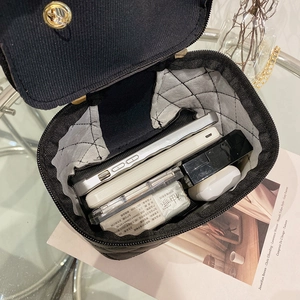 Sac seau matelassé noir avec poignée supérieure montrant un intérieur bien organisé