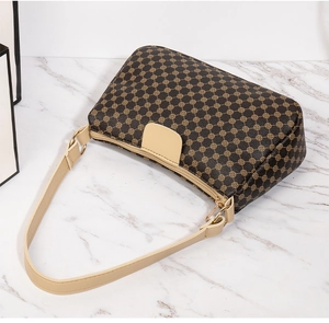 Macro detail of retro printed leather shoulder bag with gold patterns and metallic hardware