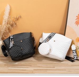 Détail de sacs seaux matelassés noir et blanc avec surpiqûres et bandoulière large à logo