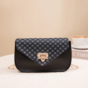 Chic black leather crossbody bag with patterned flap and gold chain strap on white fabric