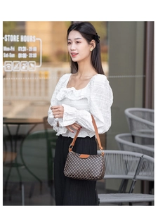 Detail of a brown checkered hobo shoulder bag styled with a white puff sleeve top