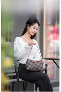Close-up of a brown checkered patterned crossbody bag on a model in a cafe setting