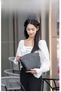 Détail du sac seau noir avec rabat matelassé et bandoulière jacquard réglable