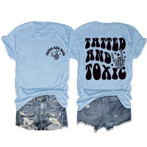Detail of tatted and toxic graphic on light blue knit tee with distressed denim shorts