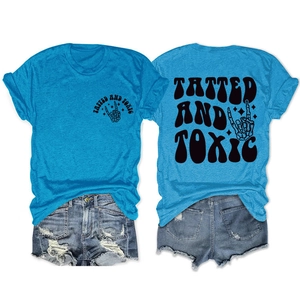 Flat lay of bright blue Tatted and Toxic t-shirt with skull hand print and denim shorts