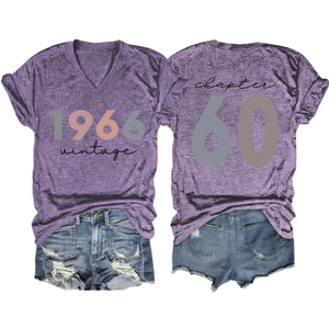 Flat lay of purple V-neck 1966 vintage tee with Chapter 60 print and denim shorts