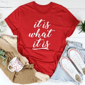 Flachbild von rotem 'it is what it is' T-Shirt mit Jeans und Sneakern auf Holz