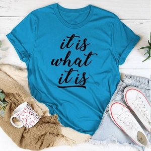 Detail eines königsblauen Baumwoll-T-Shirts mit 'it is what it is' Aufdruck und Jeansshorts