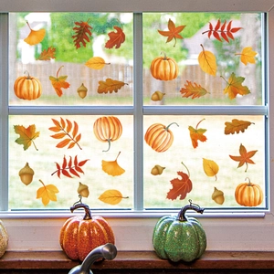 Detail of autumn window decals featuring pumpkins and maple leaves on a glass window frame