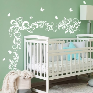 White flower vine and butterfly wall stickers on light green wall in cozy bedroom scene