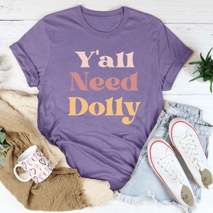 Mise à plat d'un T-shirt violet 'Y'all Need Dolly' avec short en jean et baskets