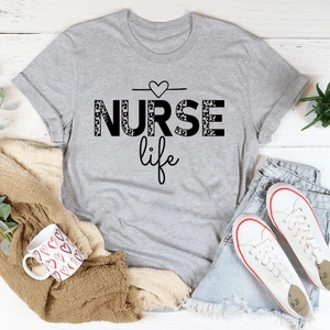 Flat lay of gray T-shirt with leopard NURSE life print on white wood background