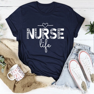 Flat lay of navy blue Nurse Life T-shirt with leopard print text on white wood floor