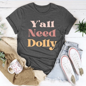 Mise à plat du t-shirt vintage Y'all Need Dolly avec style décontracté sur bois blanc