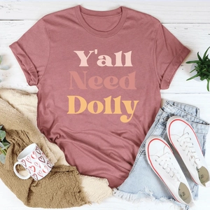 T-shirt rose poudré avec imprimé Y'all Need Dolly et accessoires d'été sur fond bois