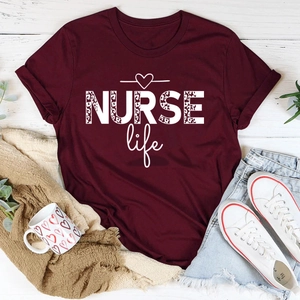 Flat lay of maroon NURSE life t-shirt with leopard print text and white canvas shoes