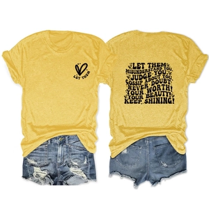 Détail de l'imprimé Let Them Misunderstand sur t-shirt jaune et short en jean vieilli