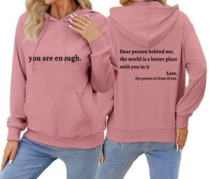 Détail du sweat à capuche rose avec cordon et texte imprimé sur la poitrine