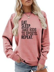 Gros plan de l'imprimé Eat Sleep Take Kids To Sports sur sweat-shirt rose
