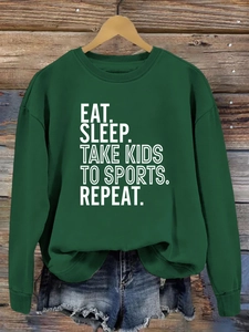 Détail du slogan Eat Sleep Take Kids To Sports imprimé sur un sweat-shirt vert foncé