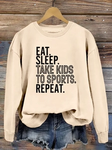 Détail du slogan imprimé Eat Sleep Take Kids sur un sweat-shirt beige à manches longues